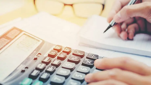 Person using a calculator and writing on a notepad estimating figures with a salary packaging calculator
